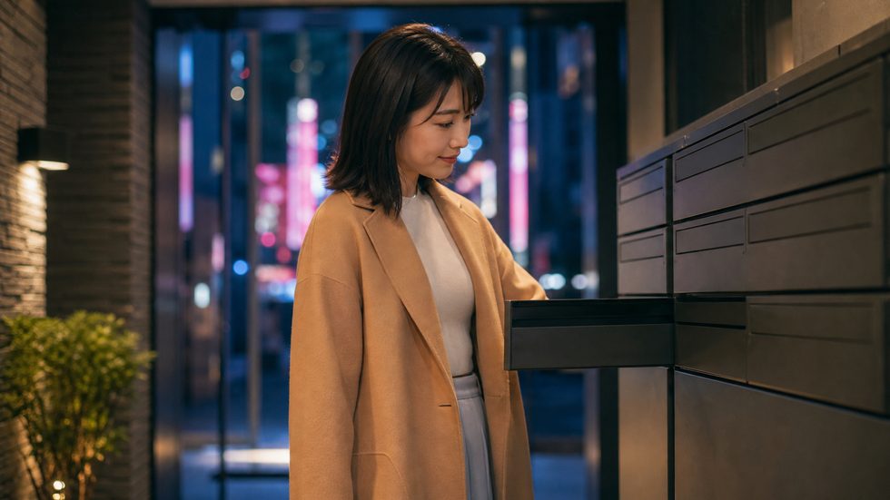 マンションの郵便受けを確認する女性（チャットレディの郵便物管理・親バレ対策イメージ）
